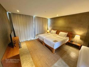 a bedroom with a large bed and a television at Inchantreedoopool in Kanchanaburi City