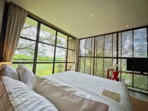 a bedroom with a large bed and large windows at Inchantreedoopool in Kanchanaburi City