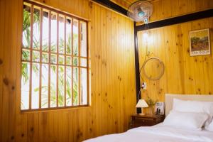 a bedroom with a wooden wall with a bed and a window at Homestay Pleiku Phố in Pleiku