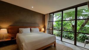 a bedroom with a bed and a large window at Inchantreedoopool in Kanchanaburi City
