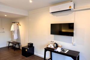 a hotel room with a television and a table with towels at Nuan Nil Secret Courtyard in Chiang Mai