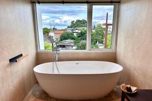 a bath tub in a bathroom with a large window at Nuan Nil Secret Courtyard in Chiang Mai +56 photos