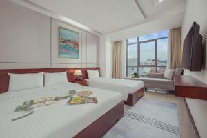 a hotel room with two beds and a couch at Star Hotel and Spa Danang in Danang