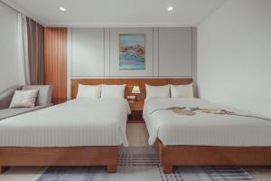 a bedroom with two beds and a chair at Star Hotel and Spa Danang in Danang