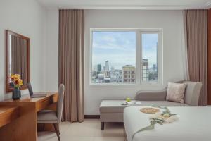 a hotel room with a bed and a desk and a window at Star Hotel and Spa Danang in Danang