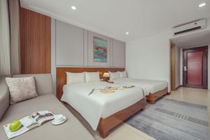 a hotel room with two beds and a couch at Star Hotel and Spa Danang in Danang