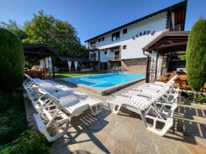 een groep witte ligstoelen naast een zwembad bij Family Hotel Bunara in Brestnik