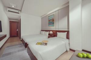 a hotel room with two beds and a table at Star Hotel and Spa Danang in Danang