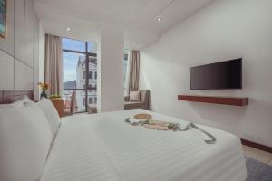 a white room with a bed and a flat screen tv at Star Hotel and Spa Danang in Danang