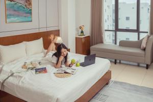 a little girl laying on a bed with a laptop at Star Hotel and Spa Danang in Danang
