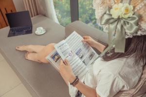 a woman sitting on a couch reading a magazine at Star Hotel and Spa Danang in Danang
