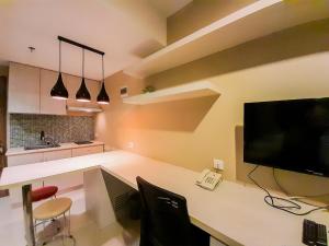 eine Küche mit einem Schreibtisch mit Computer und Fernseher in der Unterkunft Modern and Cozy Studio at Student Park Apartment By Travelio in Seturan