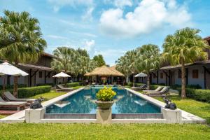 a pool at a resort with chairs and umbrellas at Malabar Pool Villa Phuket in Phuket Town