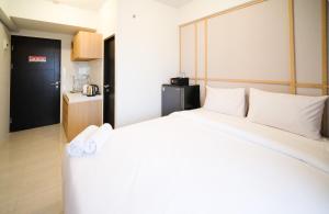 a bedroom with a large bed with white pillows at Best Choice and Strategic Location Studio at Apartment Suncity Residence By Travelio in Sidoarjo +10 photos