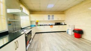 a large kitchen with white cabinets and a wooden floor at Private Cottage in Sharjah