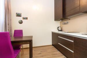 a kitchen with a wooden table and purple chairs at Apartamentai 555 in Vilnius