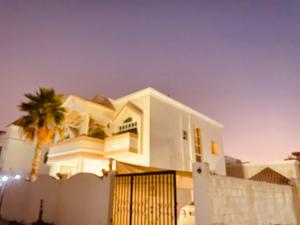 a white house with a palm tree in front of it at Private Cottage in Sharjah