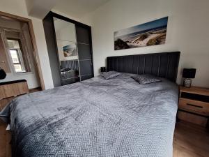 a bedroom with a large bed and two windows at JH Apartament in Kołobrzeg