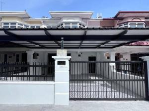 a white house with a black fence and a gate at Cozy Homestay near Pantai & Aeon Big - 10pax by Ngio in Batu Pahat