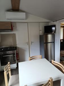 a small kitchen with a white table and chairs at MH F52 Camping Bois Masson in Saint-Jean-de-Monts +8 photos