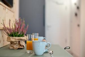 a table with two cups of orange juice and a vase of flowers at Arbio Freiburg Aparthotel in Freiburg im Breisgau