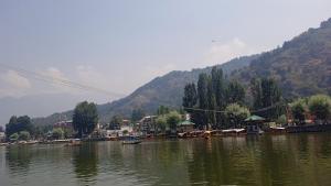 a river with a town and a mountain in the background at Island homestay in dal lake in Srinagar