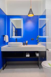 a blue bathroom with a sink and a mirror at Emil Balaban Luxury Apart-Hotel in Bucharest