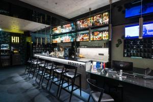 a bar with bar stools and a woman standing behind it at BOUTIQUE HOTEL11 with rooftop SPA in Nitra +62 photos