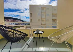 a balcony with two chairs and a table and a building at Apartamento SEREN AGUA in Moledo