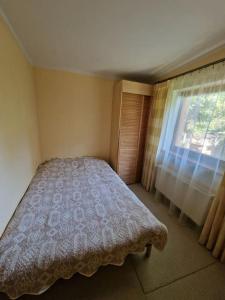 a small bedroom with a bed and a window at Ezermalas in Carnikava