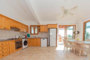 a kitchen with wooden cabinets and a table and a ceiling fan at Villa Helena in Peyia +6 photos