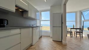 Una cocina con gabinetes blancos y una mesa con sillas. en Barmouth Beach Front Apartments, en Barmouth
