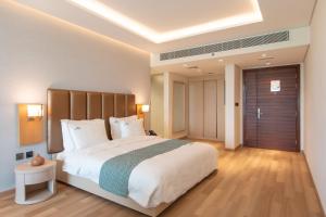 a bedroom with a large white bed and a wooden floor at Zoya Health & Wellbeing Resort in Ajman 