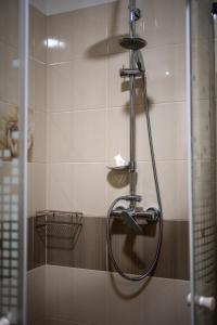a shower with a shower head in a bathroom at Holiday Apartmanház Gyula in Gyula