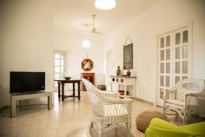 a living room with white chairs and a television at Villa Maria in Villanova di Ostuni