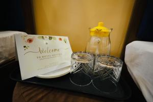a tray with a sign and two glasses and a bottle at HOTEL SHIVIKA in Bikaner