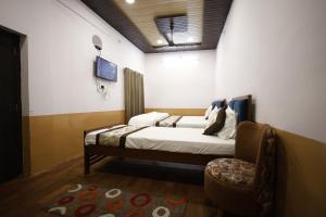 a bedroom with a bed and a chair in it at HOTEL SHIVIKA in Bikaner