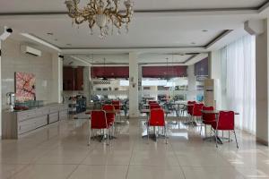 a dining room with red chairs and a chandelier at Kanasha Islami in Medan