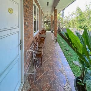 a porch with chairs and a table on a house at RedDoorz near Taman Bunga Nusantara in Pasirhuni