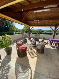 a patio with wicker chairs and tables on a roof at La Maison du Parloir in Queaux