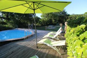 a yellow umbrella sitting on a deck next to a pool at Cabane Perchée Jurassic Piscine, Spa et Hammam proche des Gorges de l'Aveyron in Lavaurette +9 photos