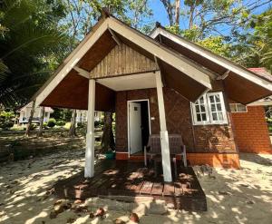 a small house with a porch and a chair at Pansand Resort in Ko Bulon Le