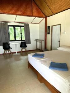 a bedroom with two beds and a table and chairs at Pansand Resort in Ko Bulon Le