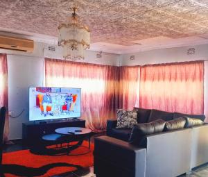 a living room with a couch and a tv at The Wild Thing Guesthouse in Serowe