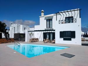 a white house with a swimming pool in front of it at Villas Volcan in Playa Blanca