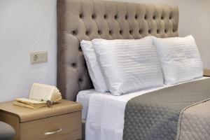 a bed with white pillows and a book on a night stand at Gkountis Garden Studio in Tsoukaladhes +15 photos