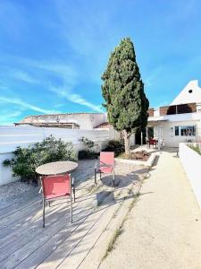 a patio with a table and two chairs and a tree at Maison, jardinet, terrasse, parking privée, climatisation in Saintes-Maries-de-la-Mer