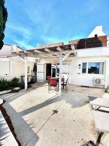a white house with a patio with a table and chairs at Maison, jardinet, terrasse, parking privée, climatisation in Saintes-Maries-de-la-Mer +4 photos