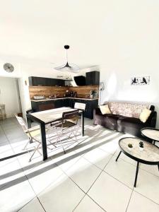 a living room with a table and chairs and a couch at Maison, jardinet, terrasse, parking privée, climatisation in Saintes-Maries-de-la-Mer
