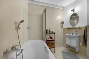 Un baño blanco con bañera y lavabo. en REVON Art-deco Apartment Laurinska, Parking options, en Bratislava 21 fotos más
